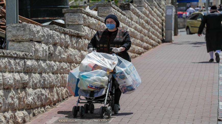 An ultra-Orthodox Jewish woman wearing a protective face mask, returns from shopping in Jerusalem's neighbourhood of Mea Shearim, on April 12, 2020, during the novel coronavirus pandemic crisis. (Photo by AHMAD GHARABLI / AFP) (Photo by AHMAD GHARABLI/AFP via Getty Images)