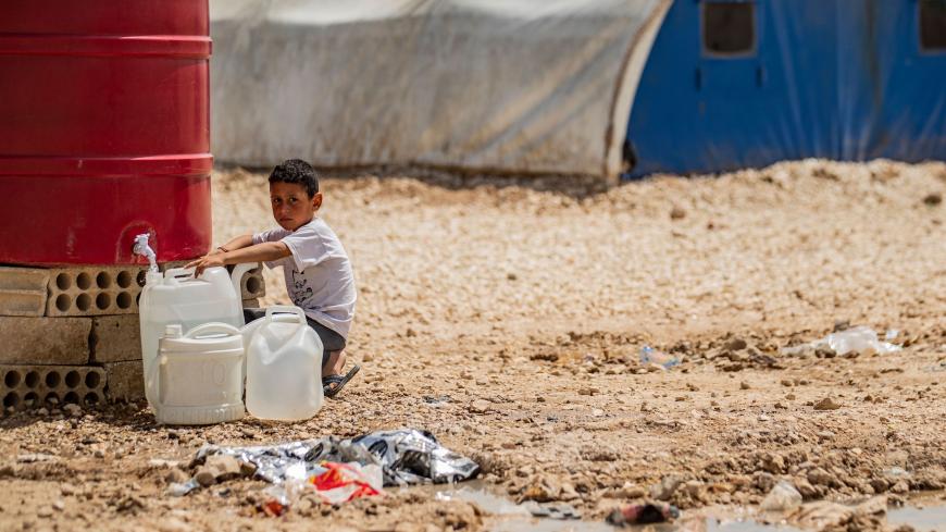 A displaced Syrian boy from Ras al-Ain, a border town controlled by Turkey and its Syrian proxies, fills jerrycans with water at the Washukanni camp in Syria's northeastern Hasakeh province on April 16, 2020. (Photo by Delil SOULEIMAN / AFP) (Photo by DELIL SOULEIMAN/AFP via Getty Images)