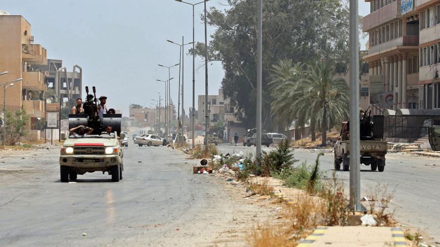 Fighters loyal to the UN-recognised Libyan Government of National Accord (GNA) ride in a technical (pickup truck mounted with turret) along a road in the Qasr bin Ghashir district south of the Libyan capital Tripoli on June 4, 2020, after the area was taken over by pro-GNA forces following clashes with rival forces loyal to strongman Khalifa Haftar. - The GNA said on June 4 that it was back in full control of the capital and its suburbs after more than a year of fighting off an offensive by eastern strongma