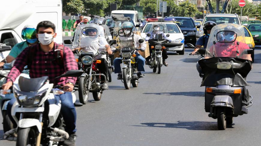 Iranians, wearing protective face masks, ride their motorcycles in the capital Tehran on July 22, 2020, during the COVID-19 epidemic. - The Islamic republic has been battling a resurgence of the virus, with official figures showing a rise in both new infections and deaths since a two-month low in May. (Photo by ATTA KENARE / AFP) (Photo by ATTA KENARE/AFP via Getty Images)