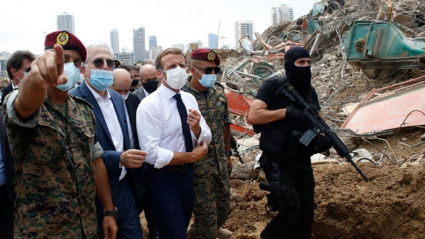 TOPSHOT - French President Emmanuel Macron (C), surrounded by Lebanese servicemen, visits the devastated site of the explosion at the port of Beirut, on August 6, 2020 two days after a massive explosion devastated the Lebanese capital in a disaster that has sparked grief and fury. - French President Emmanuel Macron visited shell-shocked Beirut on August 6, pledging support and urging change after a massive explosion devastated the Lebanese capital in a disaster that left 300,000 people homeless. (Photo by T
