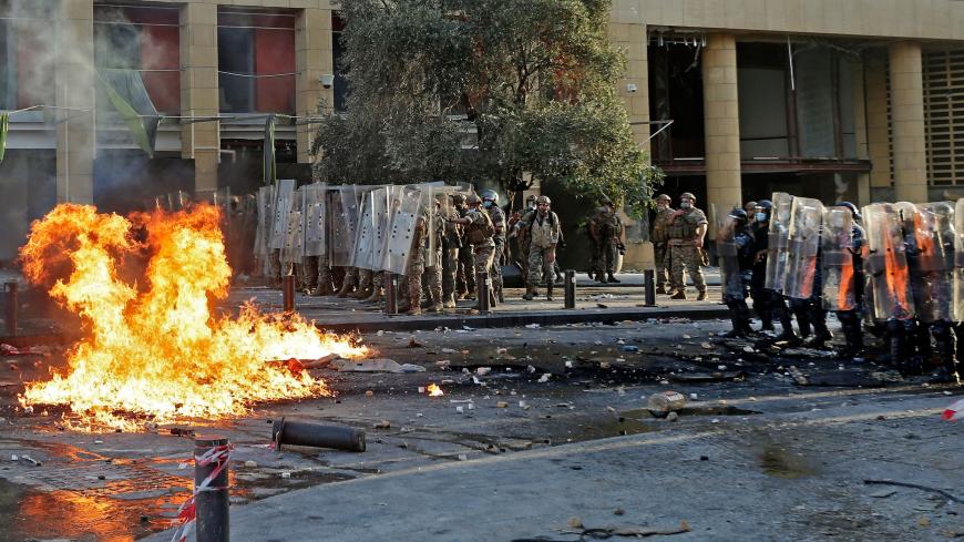 Lebanese security forces hold their position during clashes with protesters in downtown Beirut on August 8, 2020, following a demonstration against a political leadership they blame for a monster explosion that killed more than 150 people and disfigured the capital Beirut. - As security forces focused their attention on a tense demonstration a few hundred metres down the road, a group led by retired Lebanese army officers stormed the foreign ministry and declared it the "headquarters of the revolution". (Ph