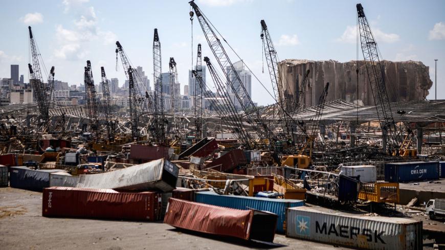 This picture taken on August 9, 2020 shows a view of destroyed freight containers before the cranes at the port of Lebanon's capital Beirut, while in the background are seen the damaged grain silos opposite the blast site of a colossal explosion due to a huge pile of ammonium nitrate that had languished for years at a port warehouse. - The huge chemical explosion that hit Beirut's port, devastating large parts of the Lebanese capital and claiming over 150 lives, left a 43-metre (141 foot) deep crater, a sec