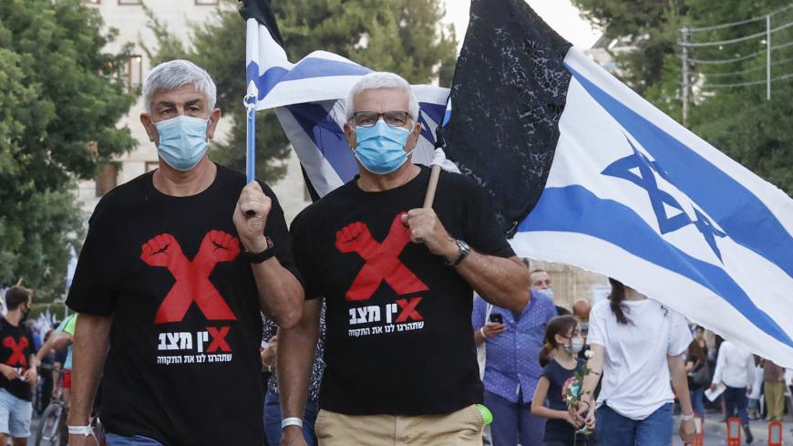 Israeli protesters wearing protective masks lift national flags during an anti-government demonstration in front of the Prime Minister's residence in Jerusalem, on August 15, 2020. (Photo by JACK GUEZ / AFP) (Photo by JACK GUEZ/AFP via Getty Images)