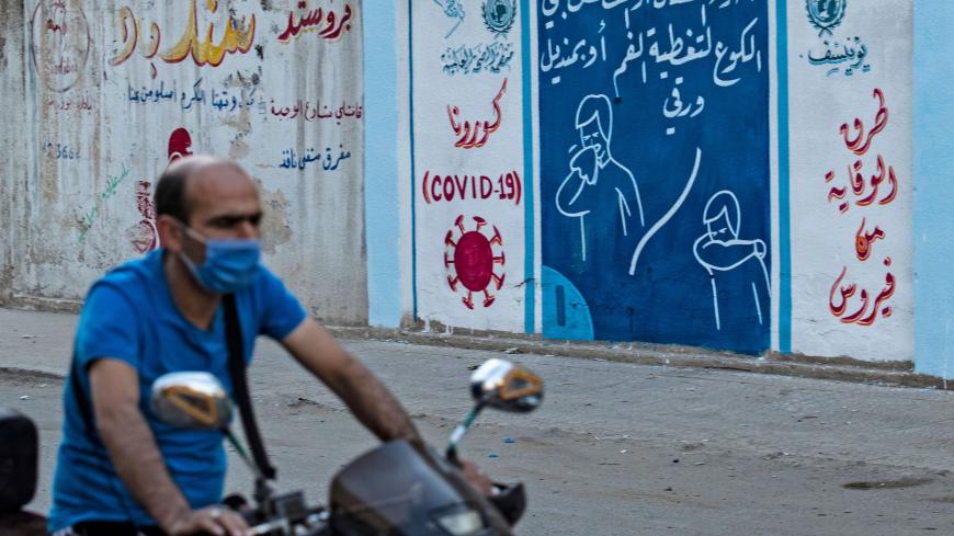 A Syrian man rides a motorbike past a mural painted as part of an awareness campaign by the United Nations International Children's Emergency Fund (UNICEF) and World Health Organization (WHO) intitative, bearing instructions on protection from COVID-19 in the Kurdish-majority city of Qamishli of Syria's northeastern Hasakeh province on August 16, 2020, after a spike in infections in the area. (Photo by Delil SOULEIMAN / AFP) (Photo by DELIL SOULEIMAN/AFP via Getty Images)