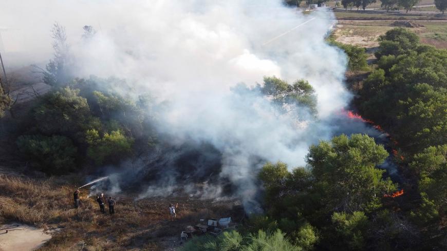 Israeli firemen extinguish a fire in a field near the Israel-Gaza border that was reportedly caused by an incendiary balloon launched from the Gaza Strip, on August 24, 2020. - Israel has bombed the Hamas-ruled coastal Palestinian strip almost daily since August 6, while balloons carrying fire bombs and, less frequently, rocket fire have hit Israel from Gaza. In retaliation for the balloon attacks and the widespread blazes on farms and scrubland they have caused, Israel has tightened its 13-year blockade of