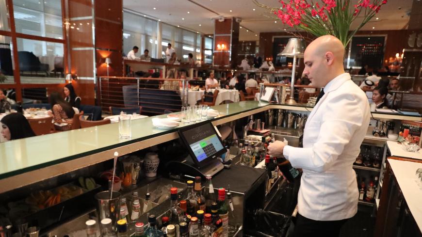 A bar tendant serves customers at a restaurant in Dubai on August 30, 2018. - As temperature levels soar in Dubai, residents and tourists in the rich Emirate turn to a much favourite indoor outing during summer days: restaurants. From business lunches, to fresh decorations, Dubais top restaurants compete to attract those costumers looking to beat the heat with a customised cool drink, or an award winning plate. (Photo by KARIM SAHIB / AFP)        (Photo credit should read KARIM SAHIB/AFP via Getty Images)