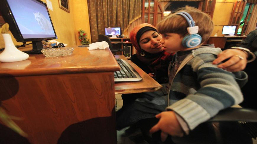 TO GO WITH AFP STORY BY INES BEL AIBAEgyptian radio presenter and divorcee Mahassen Saber takes a break from working on her Internet-based radio station "Divorcees Radio" to check on her son as he watches a film at an Internet cafe in Zagazig, 90 kms north of Cairo, on January 14, 2010. When Mahassen Saber divorced her husband after four years of difficult procedures, she did not expect to become the centre of gossip. To fight the prejudice, the young Egyptian decided to launch "Divorcees Radio". AFP PHOTO/