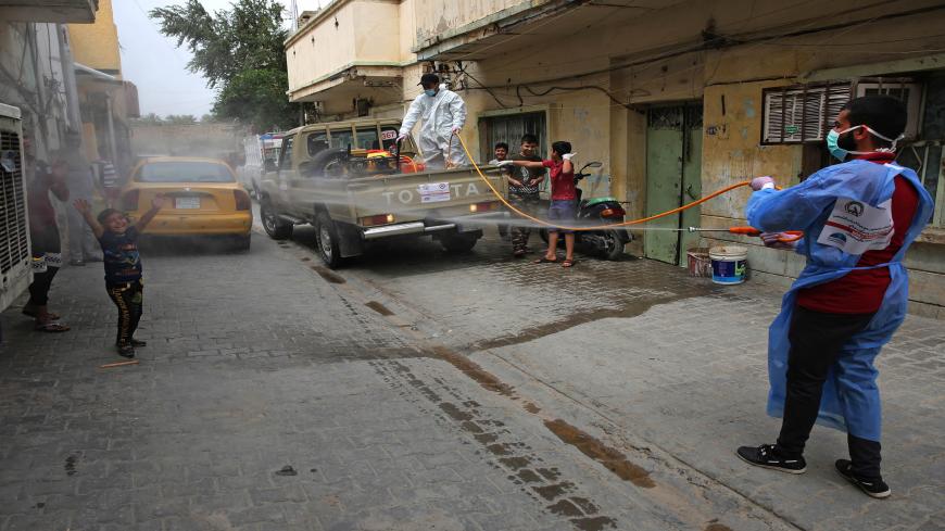 Members of the Hashed al-Shaabi (Popular Mobilisation) forces militia disinfect a street in the western Washash district of the Iraqi capital Baghdad on April 6, 2020, as part of measures against the COVID-19 coronavirus pandemic. (Photo by AHMAD AL-RUBAYE / AFP) (Photo by AHMAD AL-RUBAYE/AFP via Getty Images)