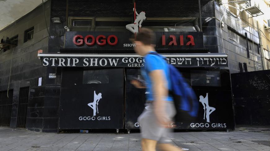 A boy walks past the closed Gogo Girls strip club in the Israeli city of Tel Aviv on March 5, 2020. - The demise of Tel Aviv's strip clubs was accelerated in 2018, when Israel's parliament, the Knesset, passed a law banning brothels. But the final straw came in April last year when the public prosecutor issued a directive to clamp down on lap dances, arguing they could in some cases be viewed as prostitution. (Photo by Emmanuel DUNAND / AFP) (Photo by EMMANUEL DUNAND/AFP via Getty Images)