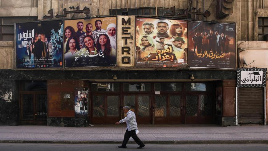 This picture taken early on May 24, 2020 shows a view of the historic Metro cinema theatre as a man walks past, along the commercial Talaat Harb street in the almost deserted city centre Egypt's capital Cairo, on the first day of Eid al-Fitr, the Muslim holiday which starts at the conclusion of the holy fasting month of Ramadan. - Egypt had previously announced a lengthening of its night-time curfew and other measures to prevent large gatherings during the Eid al-Fitr holidays. One of the most important dat