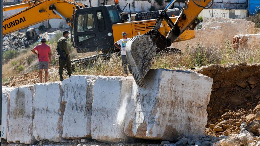 Israeli earth movers remove concrete blocks along the side of a road lying in "Area C" of the occupied West Bank where Israeli administers full civil and security control, in the flashpoint city of Hebron on July 2, 2020. (Photo by HAZEM BADER / AFP) (Photo by HAZEM BADER/AFP via Getty Images)