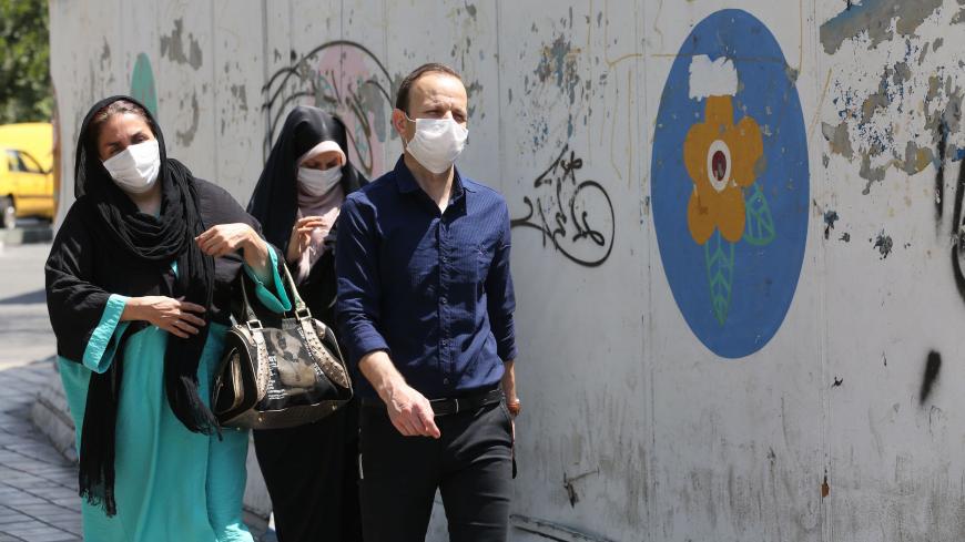 Iranians wearing face masks walk down a street in the capital Tehran amid the novel coronavirus pandemic on August 9, 2020. (Photo by ATTA KENARE / AFP) (Photo by ATTA KENARE/AFP via Getty Images)