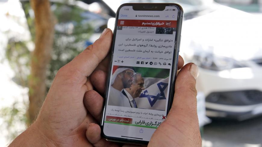 A man holds a phone while reading a story published on Tasnim News Agency's website about the recent news of a US-brokered deal between Israel and the UAE to normalise relations, in Iran's capital Tehran on August 14, 2020. - Iran strongly condemned the agreement, blasting it as an act of "strategic stupidity" that would only strengthen the Tehran-backed "axis of resistance". The Israel-UAE deal marks only the third such accord the Jewish state has struck with an Arab nation, an historic shift making the Gu