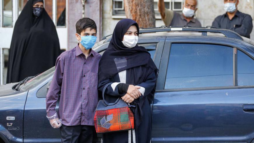A schoolboy arrives with his mother while mask-clad as part of new COVID-19 coronavirus pandemic precautions, outside Nojavanan school in Iran's capital Tehran on the first day of schools re-opening on September 5, 2020. (Photo by ATTA KENARE / AFP) (Photo by ATTA KENARE/AFP via Getty Images)