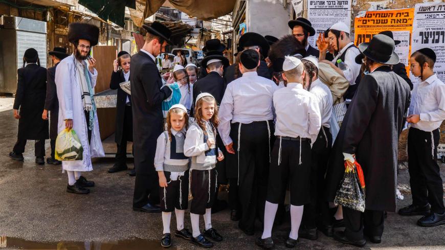 Ultra-Orthodox Jewish men and boys, a few mask-clad due to the COVID-19 coronavirus pandemic, stand along a street corner in the Ultra-Orthodox neighbourhood of Mea Shearim in Jerusalem a few hours before the start of Yom Kippur, the Jewish holy day of Atonement, on September 27, 2020. - Yom Kippur, also known as the Day of Atonement, is one of the most important holidays of the Jewish year, during which Israelis observe a period of a 25-hour fasting, reflection and prayers and during which synagogues are f