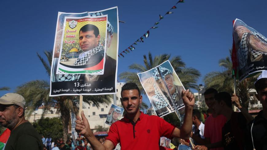 Palestinians hold pictures of late leader Yasser Arafat in Gaza City on November 9, 2017, during a festival to commemorate the 13th anniversary of his death. 
According to organisers, the event was called by exiled Palestinian politician Mohammed Dahlan (portrait), partly to celebrate a recently agreed reconciliation agreement between the major Palestinian factions Hamas and Fatah. Dahlan has been in exile in the UAE since falling out with Palestinian president Mahmud Abbas and expelled from his Fatah movem