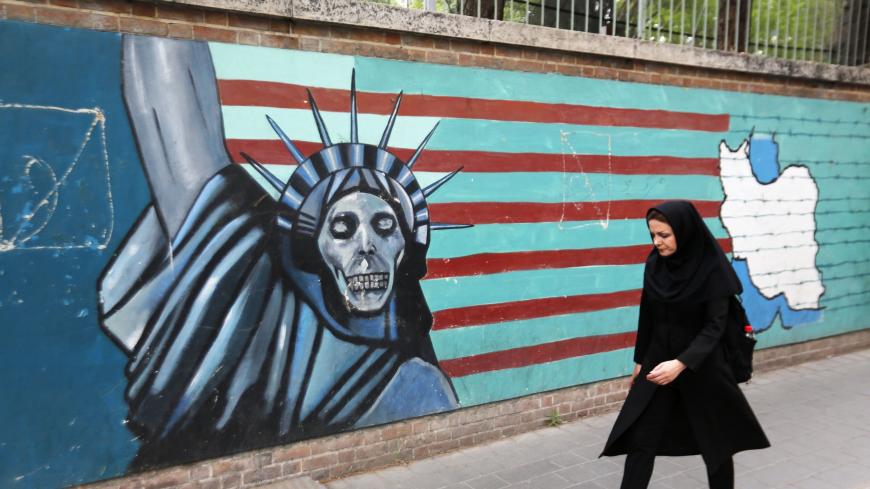 An Iranian woman walks past a mural on the wall of the former US embassy in the Iranian capital Tehran on May 8, 2018. - US President Donald Trump is due to make his decision on whether to rip up the 2015 nuclear deal and reimpose sanctions on Iran. (Photo by ATTA KENARE / AFP)        (Photo credit should read ATTA KENARE/AFP via Getty Images)