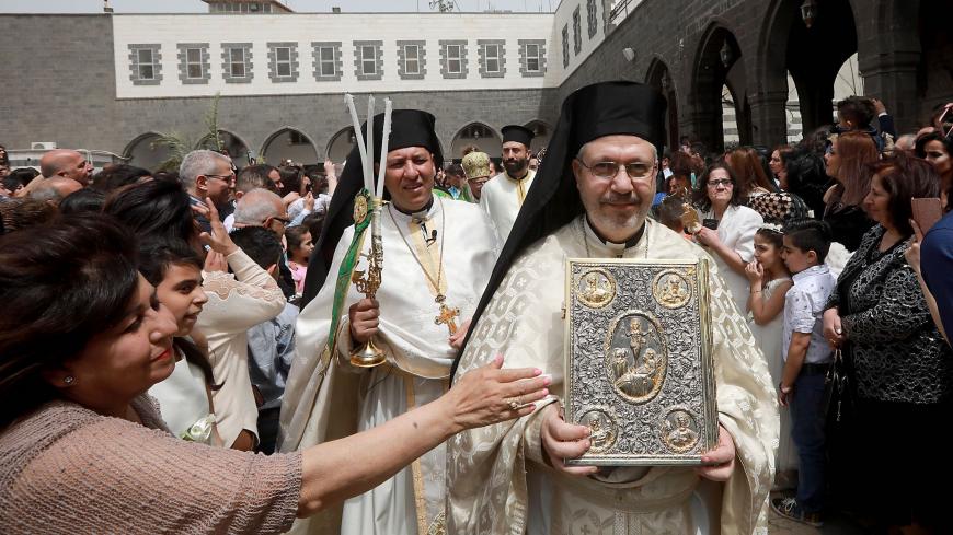 Catholic believers and clerics gather outside Greek-Melkite Patriarchal Cathedral of the Dormition of Our Lady to mark Palm Sunday in the capital Damascus in Bab Sharki, Old Damascus on April 14, 2019. (Photo by LOUAI BESHARA / AFP)        (Photo credit should read LOUAI BESHARA/AFP via Getty Images)