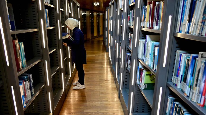 This picture taken on June 24, 2019 shows a woman standing with books in front of a shelf inside the main building of the Bibliotheca Alexandrina library in Egypt's northern coastal city of Alexandria. - The Bibliotheca, established in 2002, serves as a modern-day commemoration of the Library of Alexandria of antiquity, and a modern-day public library and educational centre. (Photo by GIUSEPPE CACACE / AFP)        (Photo credit should read GIUSEPPE CACACE/AFP via Getty Images)