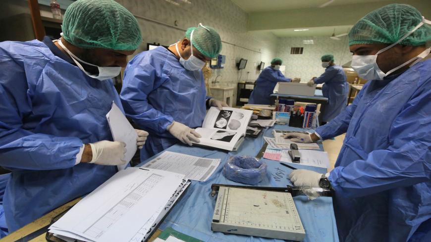Staff at Iraqi forensics lab Medico-Legal Directorate in eastern Baghdad inspect samples on June 19, 2019. - The bones, recently exhumed from mass graves in the Yazidi stronghold of Sinjar in northwest Iraq, will be compared with blood samples from surviving members of the community to help determine the fates of those still missing after the Islamic State group's 2014 sweep across their villages. Entire families were massacred, boys recruited to fight and women and girls forced into "sex slavery" in what t
