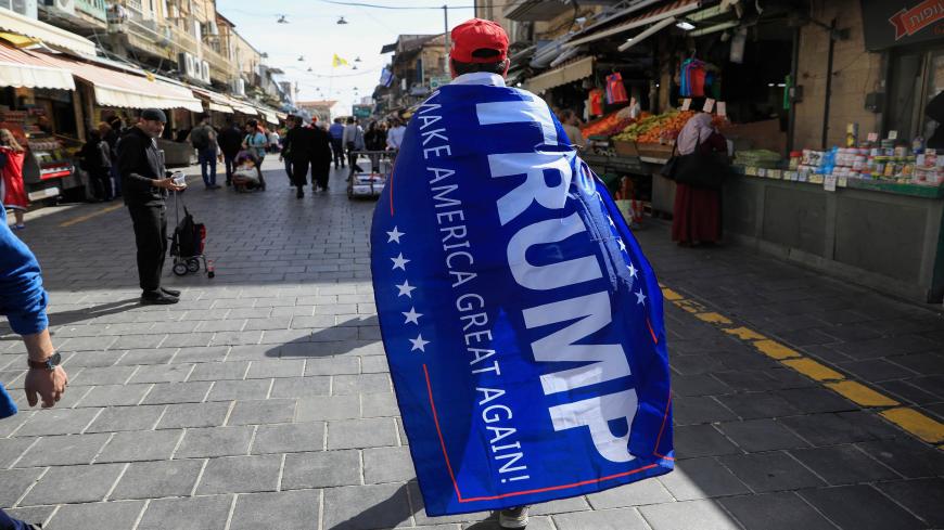 A man wrapped in a Trump campaign flag walks in Jerusalem's Mahane Yehuda market during the Jewish holiday of Purim on March 11, 2020. - Israel has imposed some of the world's tightest restrictions to contain coronavirus, but that did not stop ultra-Orthodox Jews from hitting the streets to celebrate a treasured religious custom: drinking on Purim.  Sometimes dubbed the "fun" Jewish holiday, Purim typically includes costumes and boisterous public celebrations marking a story dating from fourth-century Persi