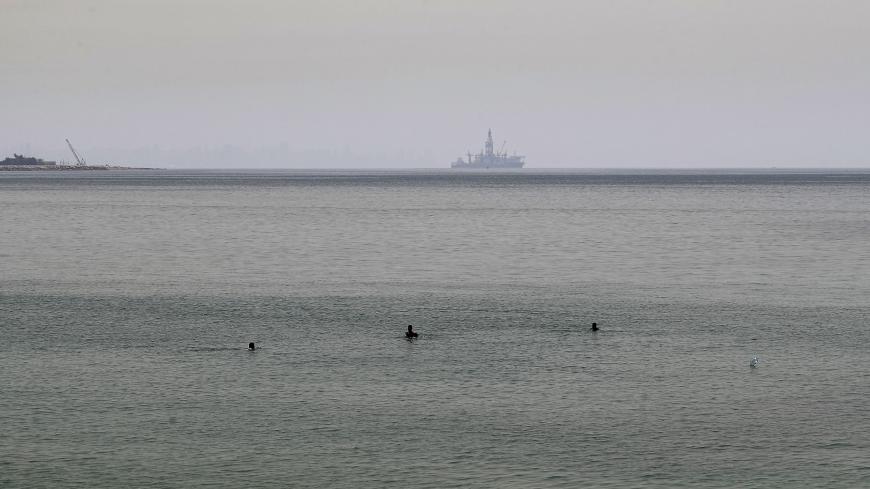 The Tungsten Explorer, an off-shore oil and gas exploration drillship, is seen in the background as people bathe in the Mediterranean water off the coast of Jounieh bay, north of Lebanon's capital Beirut, on May 19, 2020, despite beaches being legally closed due to COVID-19 coronavirus restrictions. - Lebanon gradually started lifting a COVID-19 coronavirus lockdown that has compounded its economic crisis despite an uptick in cases that prompted a four-day lockdown. Across the Mediterranean, a seasonal reco