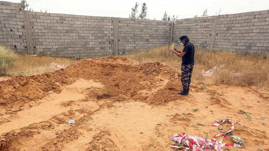 A member of security forces affiliated with the Libyan Government of National Accord (GNA)'s Interior Ministry takes a picture as he stands at the reported site of a mass grave in the town of Tarhuna, about 65 kilometres southeast of the capital Tripoli on June 11, 2020. - The United Nations mission to Libya on June 11 voiced "horror" over the reported discovery of at least eight mass graves in an area evacuated this month by strongman Khalifa Haftar's forces. "UNSMIL notes with horror reports on the discov