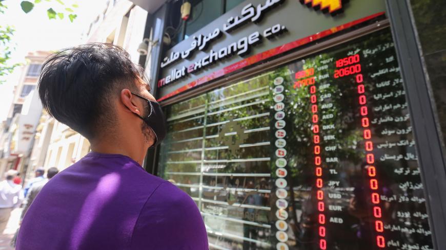 An Iranian youth, wearing a protective mask due to the COVID-19 pandemic, checks the currency exchange rates in Tehran on June 22, 2020. (Photo by ATTA KENARE / AFP) (Photo by ATTA KENARE/AFP via Getty Images)