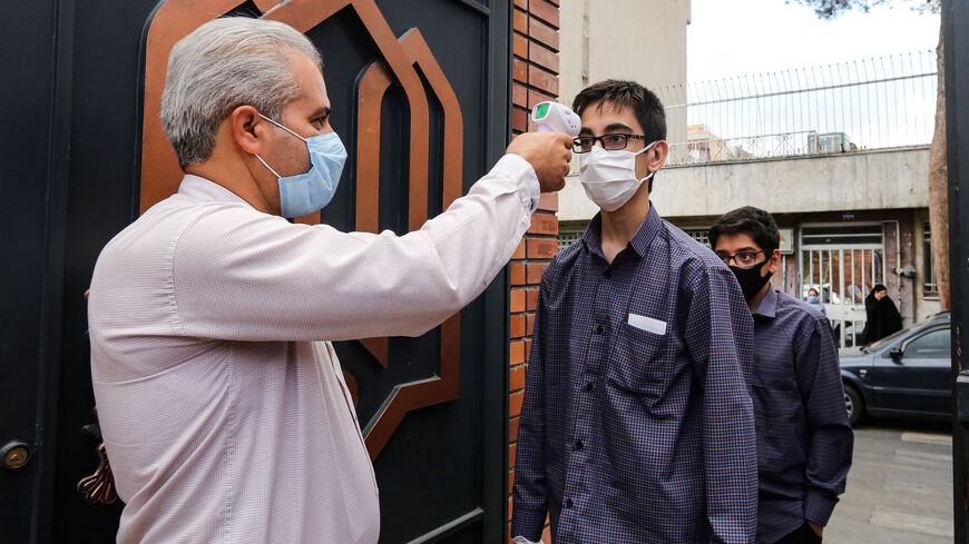 Mask-clad school children have their body temperatures measured, as part of new COVID-19 coronavirus pandemic school precautions, as they enter Nojavanan school in Iran's capital Tehran on the first day of schools re-opening on September 5, 2020. (Photo by ATTA KENARE / AFP) (Photo by ATTA KENARE/AFP via Getty Images)