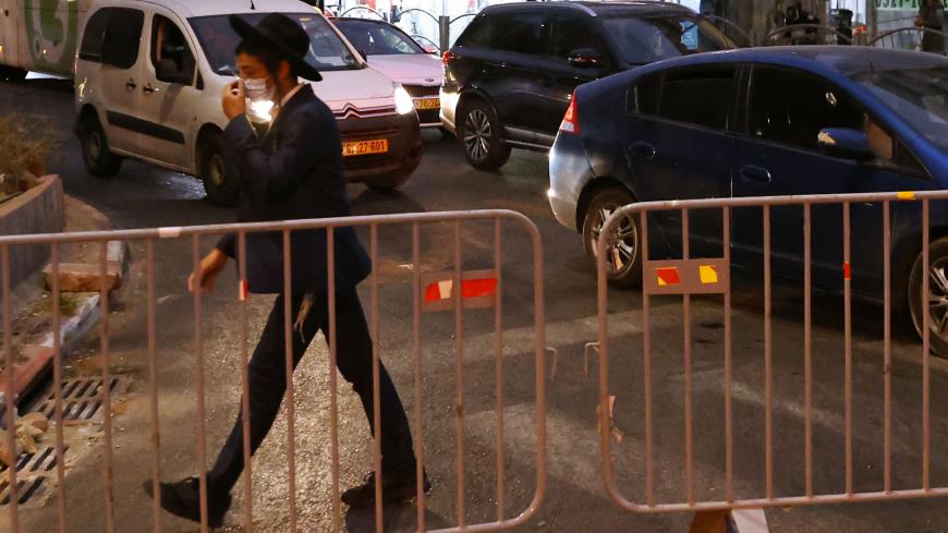 An ultra-Orthodox Jewish youth walks past a barrier set up by Israeli police on the road in the religious Israeli city of Bnei Brak, near Tel Aviv, amid measures put in place by Israeli authorities in a bid to stop the spread of Covid-19, on September 8, 2020. - In March, Bnei Brak was an initial "rebel" against the government's coronavirus rules, compelling authorities to deploy soldiers to help police impose containment measures. But after infection rates peaked across the country, Israel on Monday impose