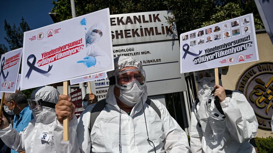 Health workers and doctors wearing personal protective equipment (PPE) hold placards reading "You cannot manage, we are dying - We are running out" during a demostration against goverments health policy on September 15, 2020 in front of Istanbul University medical faculty. (Photo by Ozan KOSE / AFP) (Photo by OZAN KOSE/AFP via Getty Images)