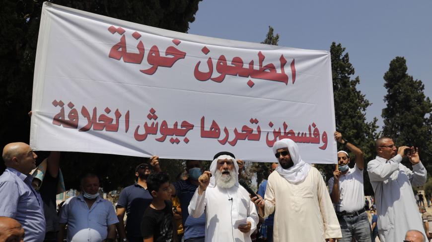 Palestinian Muslim worshippers hold a protest sign against the normalisation of ties between Israel and two Arab states, during Friday noon prayers at the al-Aqsa mosque compound in the old city of Jerusalem on September 18, 2020. - Israeli Prime Minister Benjamin Netanyahu and the foreign ministers of Bahrain and the United Arab Emirates signed agreements establishing full diplomatic ties at a ceremony at the White House. (Photo by Ahmad GHARABLI / AFP) (Photo by AHMAD GHARABLI/AFP via Getty Images)
