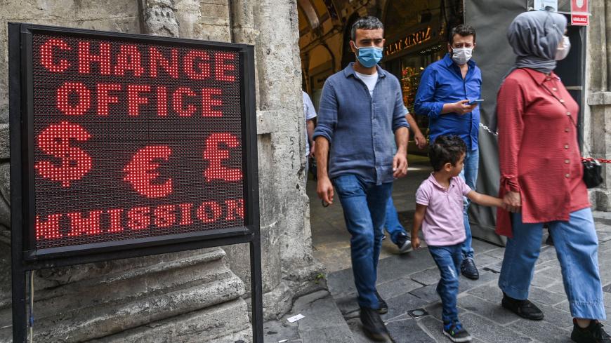 People walk past a screen near a currency exchange agency near Grand bazaar, in Istanbul, on September 24, 2020. - Turkey's central bank on September 24, 2020 raised its main interest for the first time since September 2018, boosting the rate by two percentage points to help the lira recover from historic lows. (Photo by Ozan KOSE / AFP) (Photo by OZAN KOSE/AFP via Getty Images)