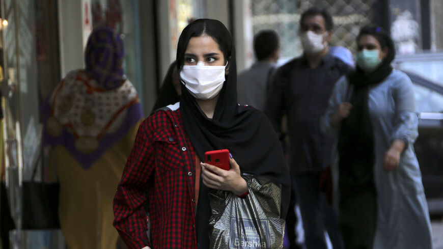 A woman, mask-clad as a COVID-19 coronavirus pandemic precaution, walks past shops along a street in Iran's capital Tehran on September 27, 2020. (Photo by ATTA KENARE / AFP) (Photo by ATTA KENARE/AFP via Getty Images)