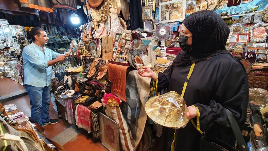A woman views a Turkish coffee set as a vendor arranges souvenir merchandise at a bazaar in Libya's capital Tripoli on September 28, 2020. (Photo by Mahmud TURKIA / AFP) (Photo by MAHMUD TURKIA/AFP via Getty Images)