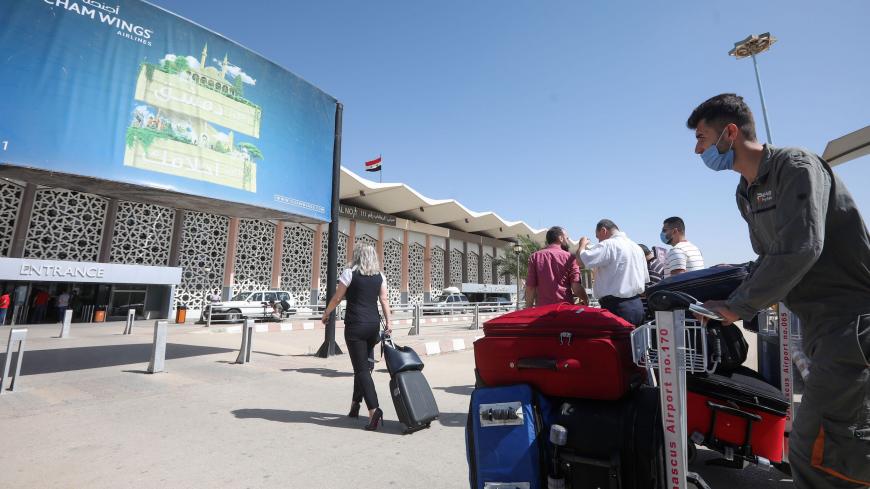 Passengers, wearing protective face masks, arrive at the Damascus International airport in the Syrian capital on October 1, 2020. (Photo by LOUAI BESHARA / AFP) (Photo by LOUAI BESHARA/AFP via Getty Images)