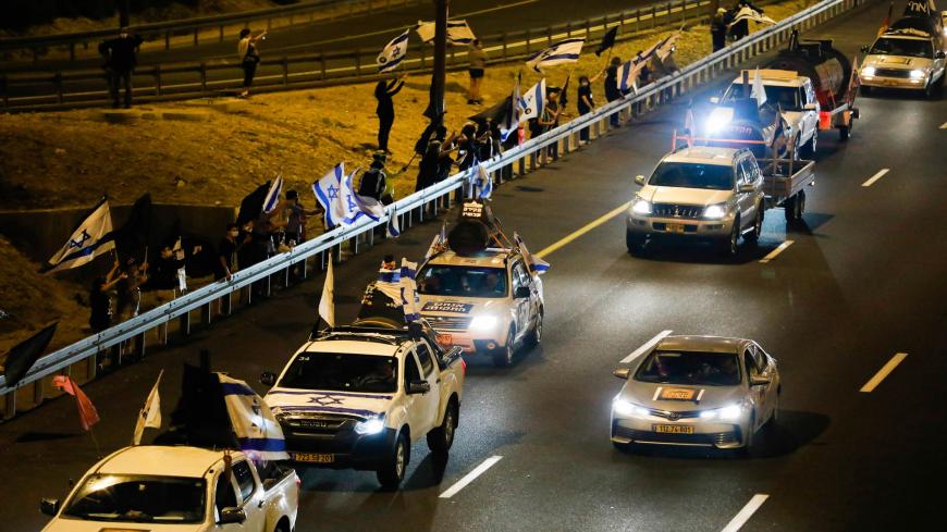 Drivers on the highway leading to Jerusalem wave Israeli national flags as they protest against the prime minister and against the second nationwide lockdown imposed by the government in a bid to stem the increase of COVID-19 infection cases, at the entrance of Jerusalem on October 14, 2020. (Photo by Ahmad GHARABLI / AFP) (Photo by AHMAD GHARABLI/AFP via Getty Images)