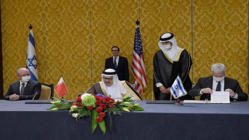 US Treasury Secretary Steve Mnuchin (back) attends a signing ceremony between the head of the Israeli delegation, National Security Advisor Meir Ben Shabbat (L) and Bahraini Foreign Minister Abdullatif bin Rashid Al-Zayani (C), in the Bahraini capital Manama on October 18, 2020. - Israel and Bahrain cemented a deal officially establishing relations and signed several memorandums of understanding, further opening up the wealthy Gulf region to the Jewish state. (Photo by Mazen Mahdi / AFP) (Photo by MAZEN MAH