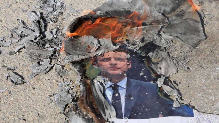 A picture of French President Emmanuel Macron is burned by Palestinians during a demonstration against him at the Palestine Technical University in al-Aroub, north of the West Bank city of Hebron, on October 27, 2020. - Calls to boycott French goods are growing in the Arab world and beyond, after President Emmanuel Macron criticised Islamists and vowed not to "give up cartoons" depicting the Prophet Mohammed. Macron's comments came in response to the beheading of a teacher, Samuel Paty, outside his school i