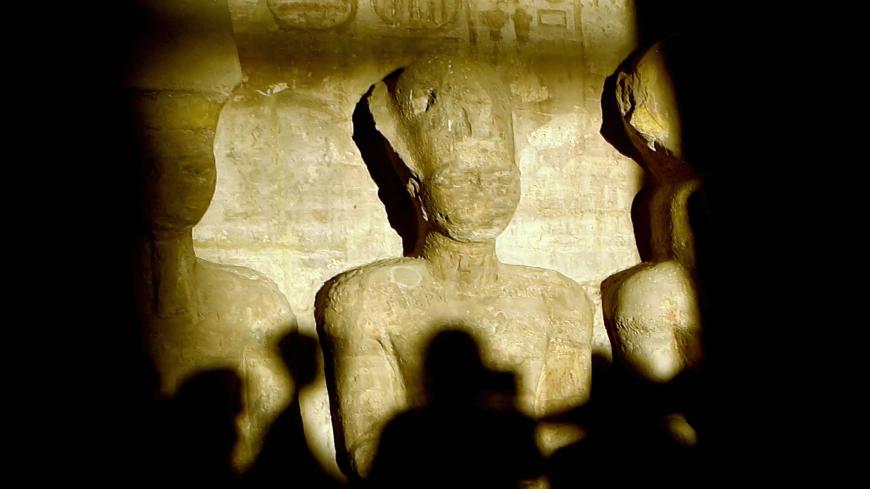 A picture taken in 2002 shows tourists casting their shadows as a ray of light illuminates the statue of Ramses II inside the temple of Abu Simbel, south of Aswan, in upper Egypt. More than 2500 tourists witnessed 22 October 2007 the sun illuminating the inner sanctuary, which happens only twice a year with a wide belief among archaeologists that the two days mark Ramsis II's birthday and day of coronation. AFP PHOTO/KHALED DESOUKI (Photo credit should read KHALED DESOUKI/AFP via Getty Images)