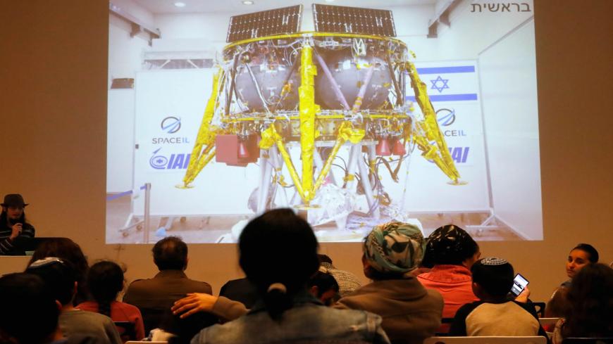 People watch a screen showing explanations of the landing of Israeli spacecraft, Beresheet's, at the Planetaya Planetarium in the Israeli city of Netanya, on April 11, 2019 before it crashed during the landing. (Photo by JACK GUEZ / AFP)        (Photo credit should read JACK GUEZ/AFP via Getty Images)
