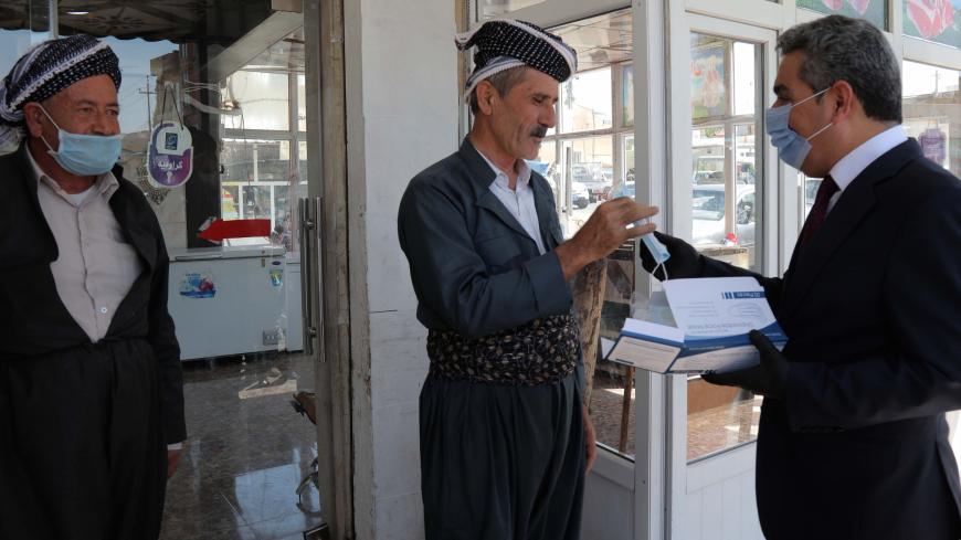 Firsat Sofi (R), the governor of Arbil, gives mask to people to protect themselves against the coronavirus COVID-19, on June 4, 2020 in Arbil, the capital of the autonomous Kurdish region of northern Iraq. (Photo by SAFIN HAMED / AFP) (Photo by SAFIN HAMED/AFP via Getty Images)