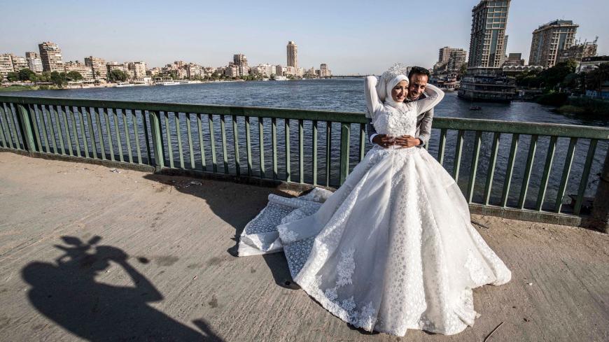 Ragab Uwais, 29, poses for a picture with his bride before a video cameraman for their wedding video along al-Gamaa bridge connecting the Egyptian capital Cairo with its twin city of Giza, on June 11, 2020. (Photo by Khaled DESOUKI / AFP) (Photo by KHALED DESOUKI/AFP via Getty Images)