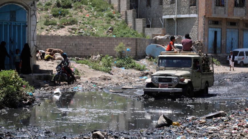 A jeep drives in a street flooded with open sewers and covered with scattered rubbish in Yemen's third city of Taez, on September 19, 2020. - Human Rights Watch warned of "deadly consequences" as a result of the obstruction of aid in war-torn Yemen, where the humanitarian effort has already been badly hit by the coronavirus crisis. Interviews with 35 humanitarian workers, 10 donor officials and 10 Yemeni health workers revealed a complex web of restrictions that hinder the flow of aid. (Photo by AHMAD AL-BA