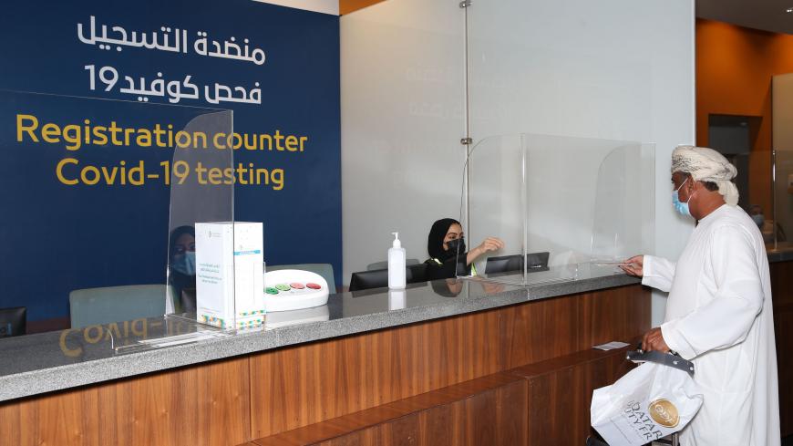 A passenger, wearing a protective face mask due to the Covid-19 pandemic, checks-in at the testing counter at the Muscat international airport in the Omani capital on October 1, 2020. (Photo by MOHAMMED MAHJOUB / AFP) (Photo by MOHAMMED MAHJOUB/AFP via Getty Images)