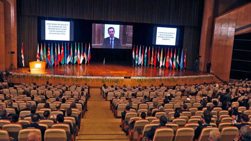 Syria's President Bashar al-Assad (on screen) addresses via video link the opening session of the international conference on the return of refugees held in Damascus on November 11, 2020. - Syria's government kicked off a two-day Russia-backed conference in Damascus towards facilitating the return of millions of Syrian refugees to the war-torn country, despite reservations within the international community. (Photo by LOUAI BESHARA / AFP) (Photo by LOUAI BESHARA/AFP via Getty Images)