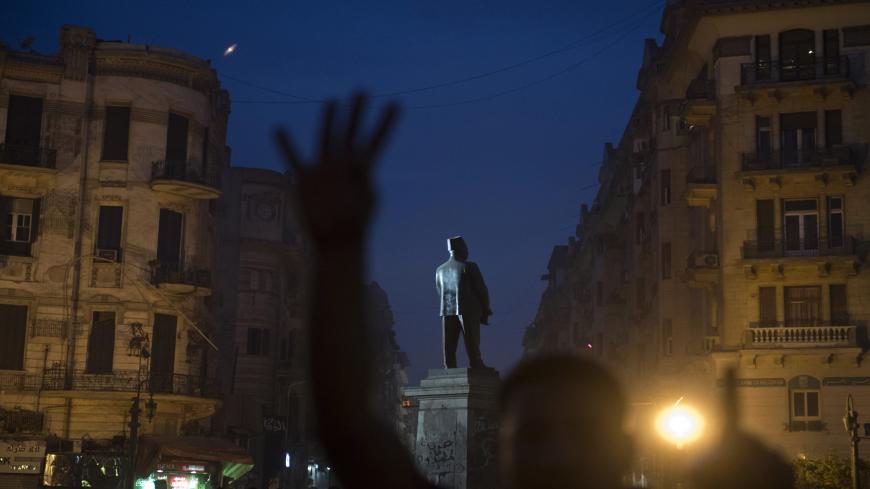 An Egyptian Muslim brotherhood supporter flashes the four-finger sign in front of a statue of Talaat Harb during a demonstration on the eponymous Square near Tahrir square on December 1, 2013 in Cairo. Protesters were chanting on Tahrir square "Down with the military regime!", "People want the fall of the regime!" and "Rabaa Rabaa", as demonstrators flashed a four-finger sign that has become associated with a government crackdown on pro-Morsi supporters in Cairo's Rabaa al-Adawiya square on August 14. AFP P