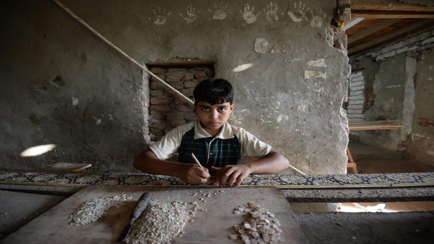 Egyptian boy Abbas Ali, 12, looks on as he works at a shop specialised in seashell wood inlays in the Saqyat al-Manqadi village in the Egyptian Nile Delta province of al-Minufiyah, on July 7, 2018. (Photo by Mohamed el-Shahed / AFP)        (Photo credit should read MOHAMED EL-SHAHED/AFP via Getty Images)