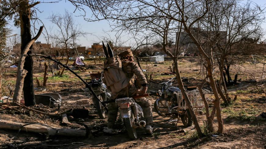 TOPSHOT - A fighter with the Syrian Democratic Forces (SDF) sits on a motorcycle at a makeshift camp for Islamic State (IS) group members and their families in the town of Baghouz, in the eastern Syrian province of Deir Ezzor, on March 9, 2019. - Pushed flush along a bend in the Euphrates River, the scrap of a desert hamlet that is Baghouz in eastern Syria is the only territory IS jihadists have left. (Photo by Dylan COLLINS / AFP)        (Photo credit should read DYLAN COLLINS/AFP via Getty Images)
